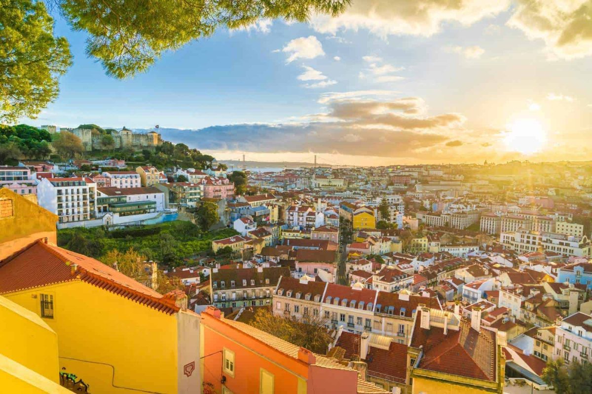Down the hill view of Lisbon: colourful houses and brown roofs mingled with parks at sunset