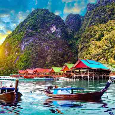 A beach in Phuket at a dawn, colorful boats on the water.