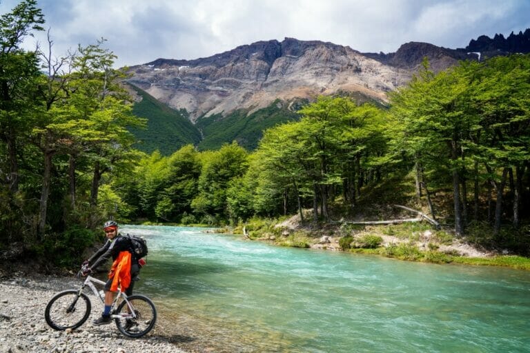 A mountain cyclist in the Andes, a river in the backgorund.