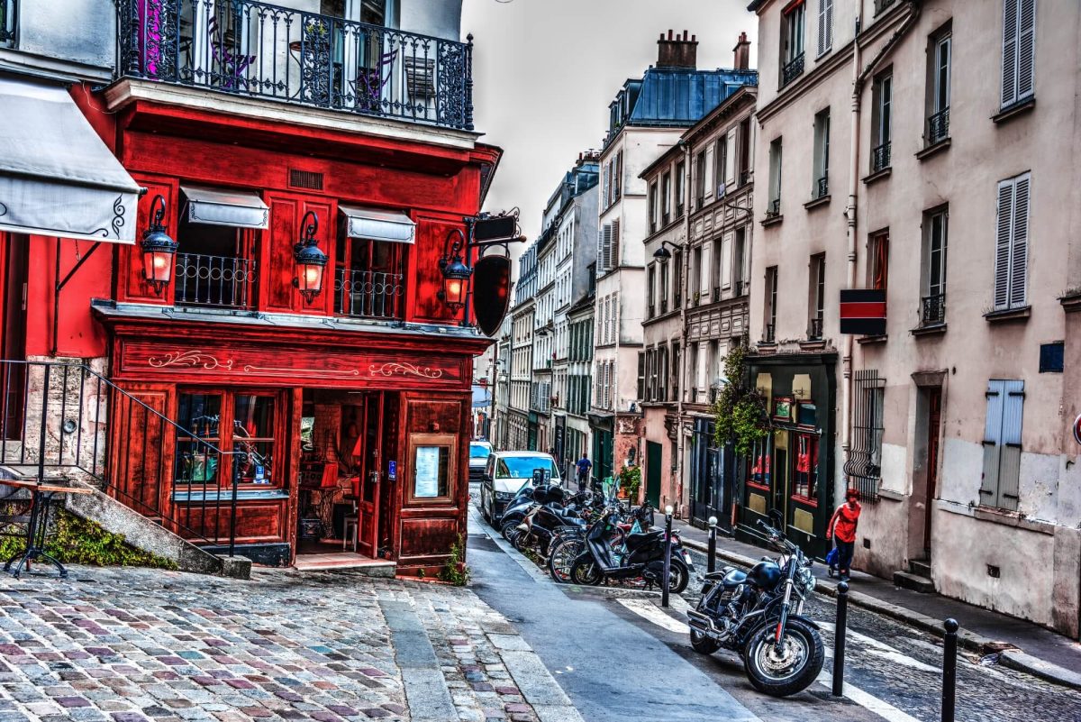 A red residential building with beautiful balconies on the corner of Montmartre in Paris