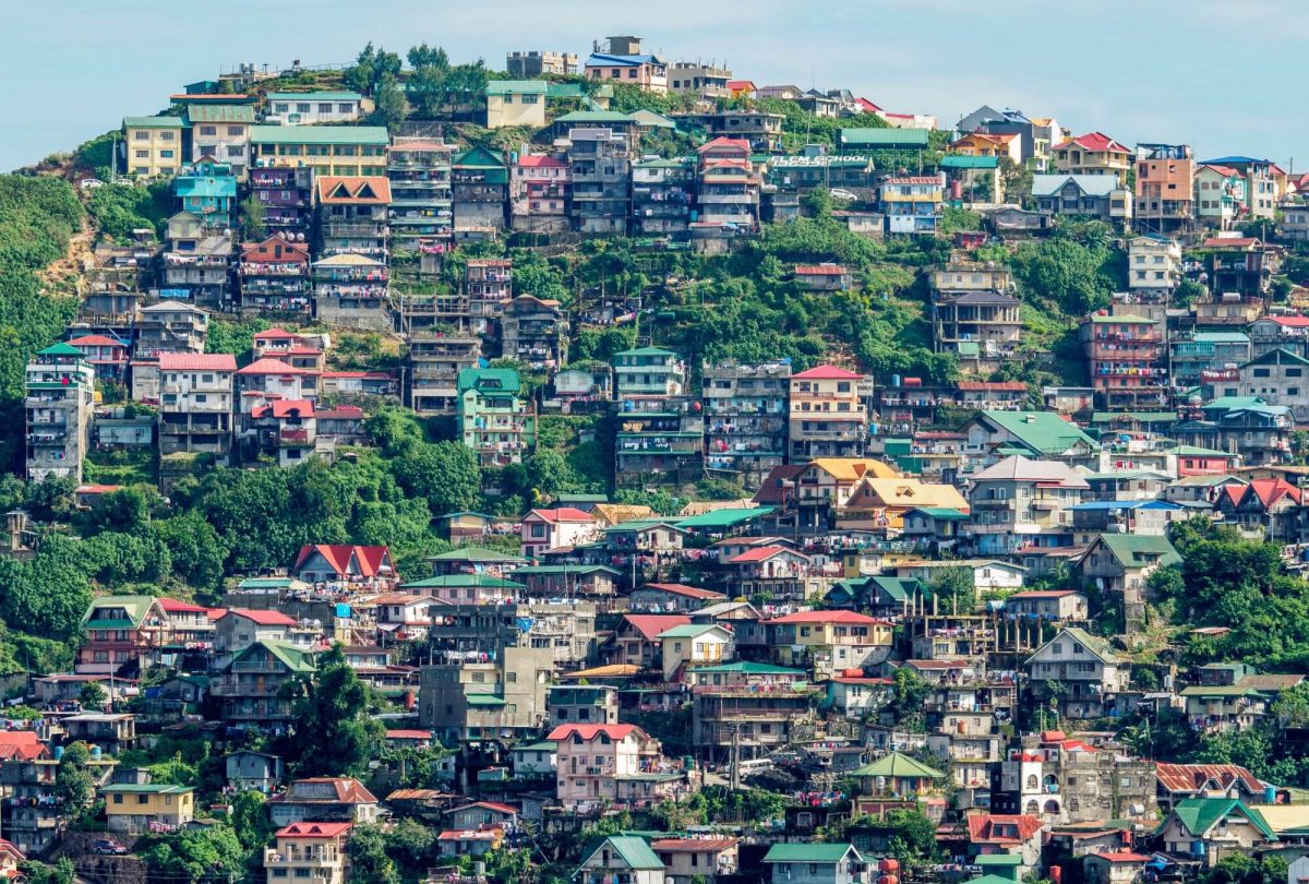 Tens of colorful houses perched on a green hill in the city of Baguio, the Philippines