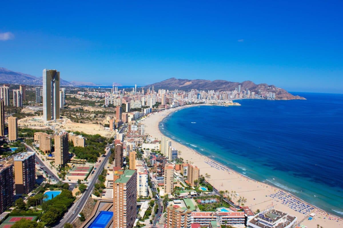 A coastal city with a long stretch of a sandy beach running along the line of tall buildings