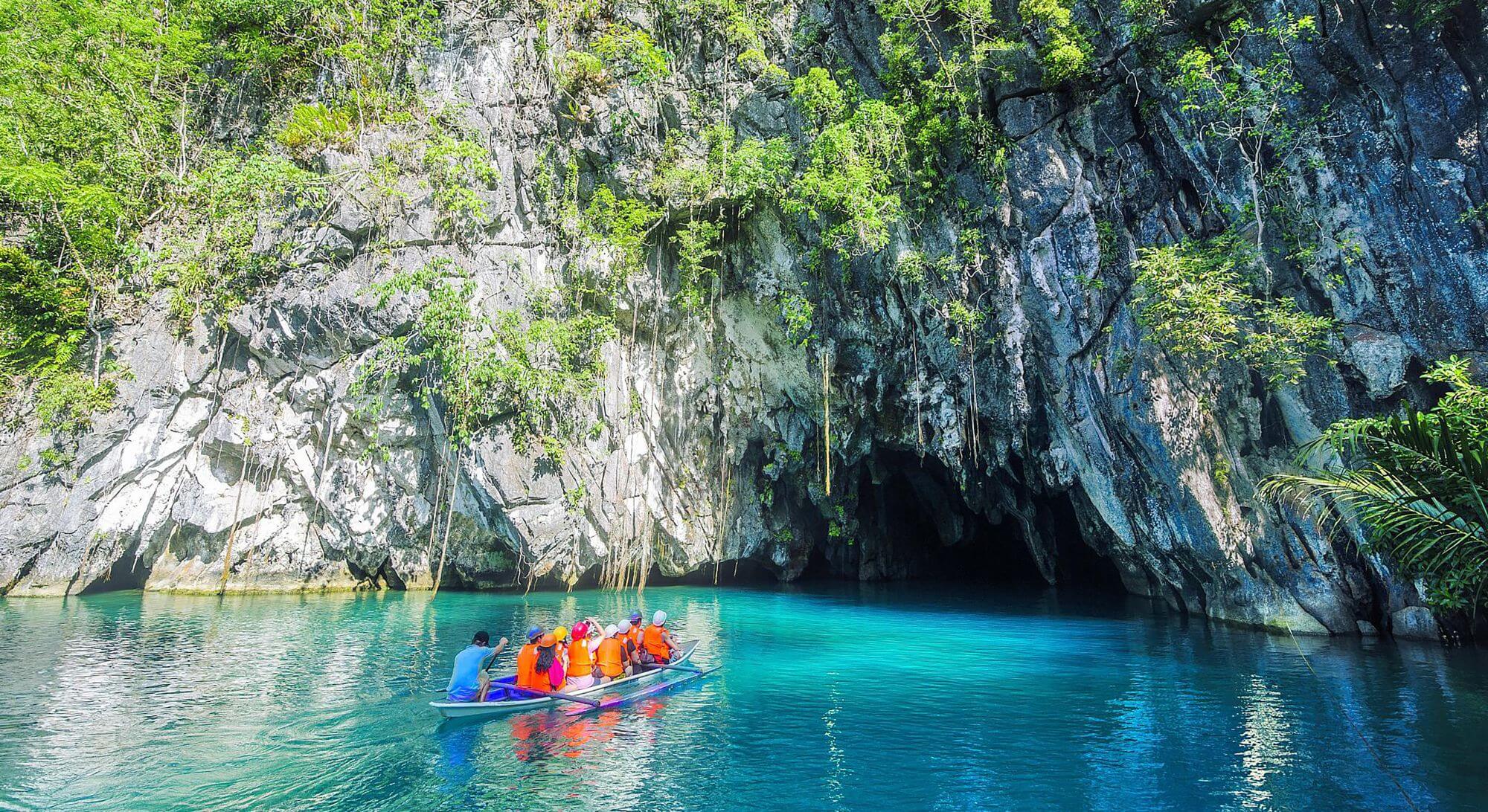Tourists in a boat enetring a cave to explore an undeground river in Puerto Princesa in the Philippines