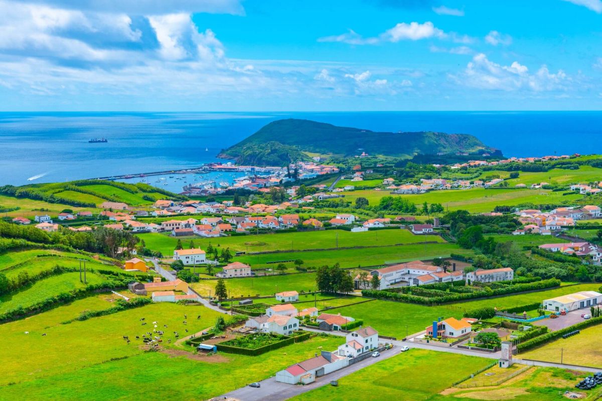 A pretty city of Horta on the coast of Faial Island - green fields, traditional red roofs and the sea in the background