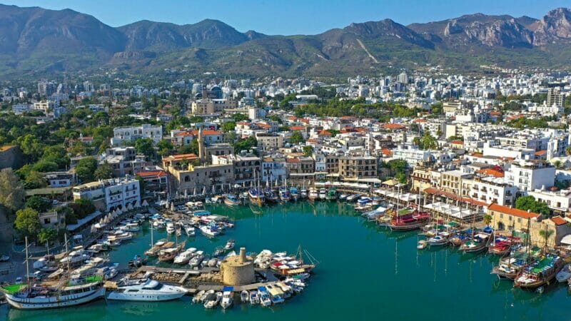 Kyrenia harbor - drone view: boats and yachts in the harbor surrounded by old historical builings and the muntains in the background