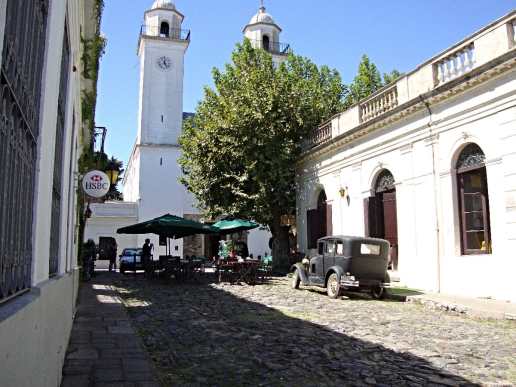An old street in Colonia-del-Sacramento, Uruguay, a street cafe and old cars parked along.